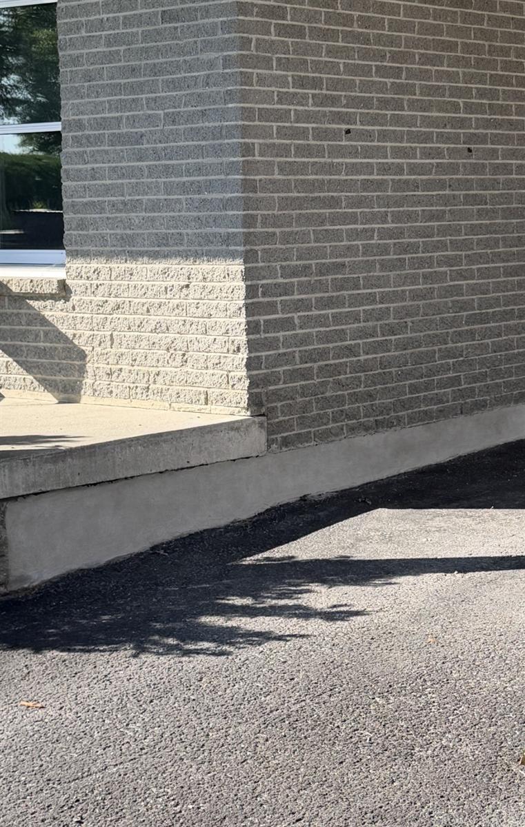 Bas de fondation en béton reconstruit et fini le long d'un mur de brique
