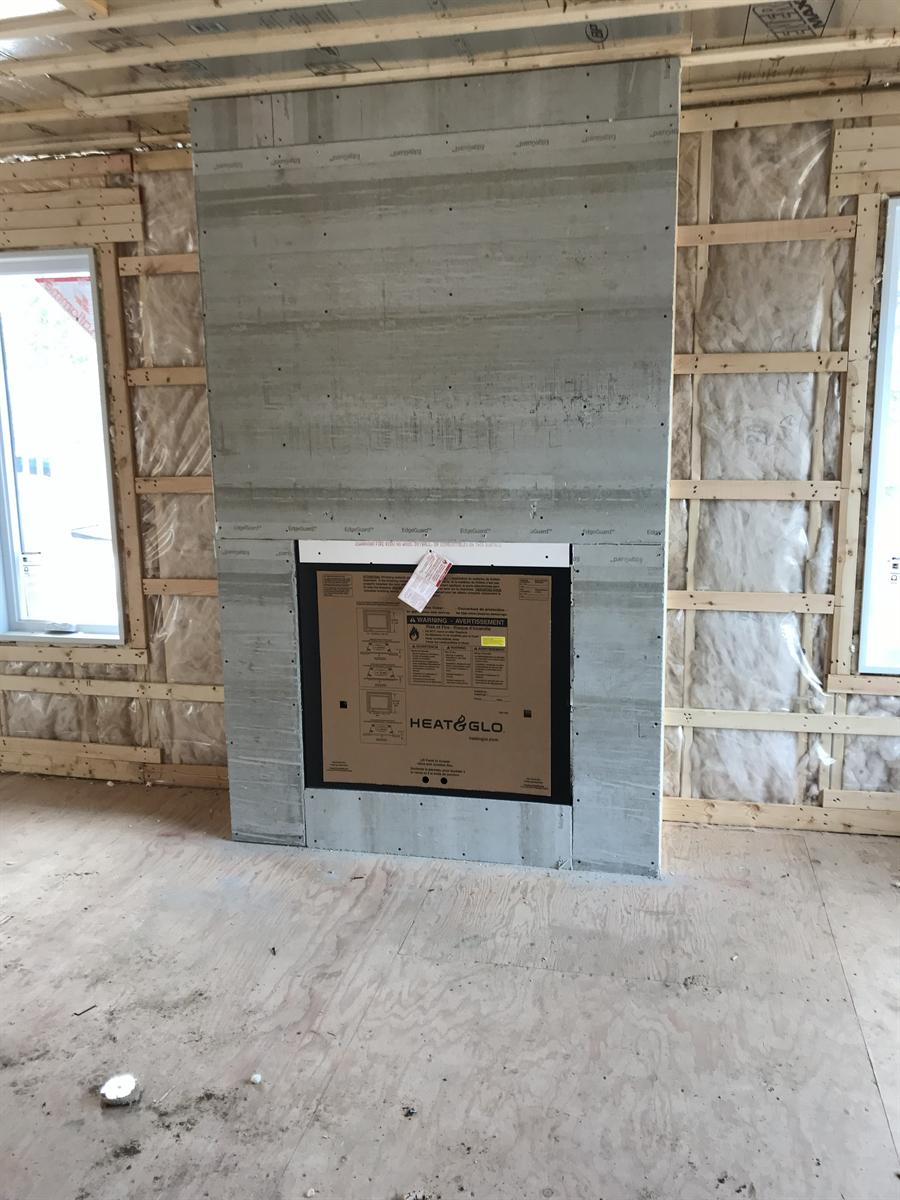 Mur de foyer préparé avec panneaux de ciment et foyer encastré, avant la pose de la pierre